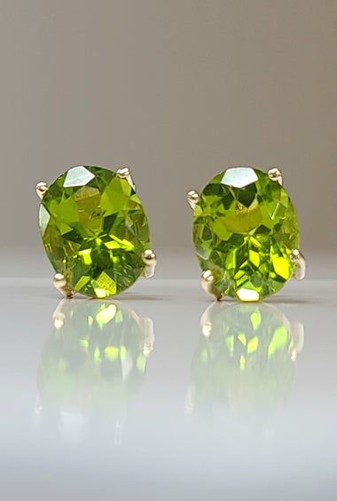 Yellow gold peridot stud earrings with cushion-cut green gemstones in bezel prongs