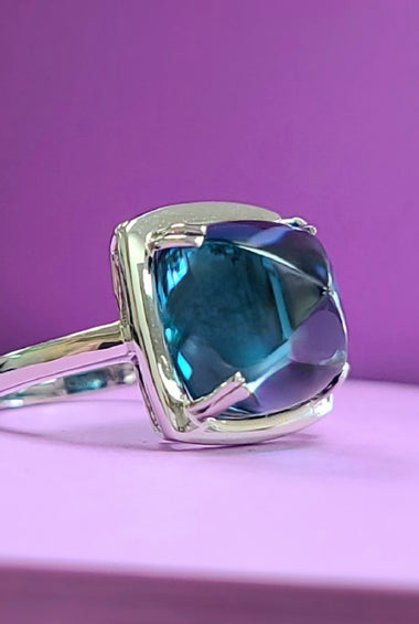 White gold ring with cushion-cut blue topaz bezel setting