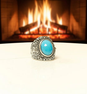 Silver ring with a turquoise stone in front of a fireplace