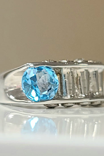 Sterling silver ring with oval blue topaz and baguette diamond accents