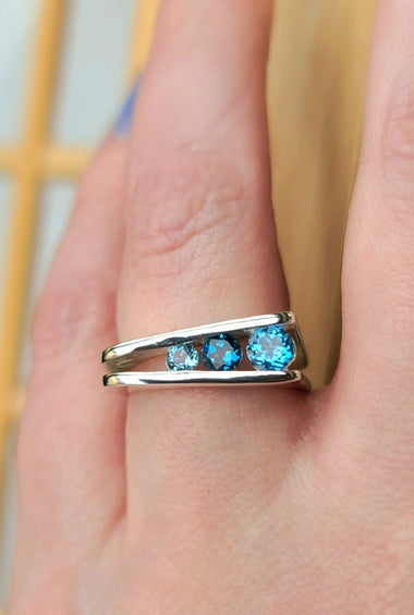 Sterling silver 3-stone corner ring with three blue gemstones on a slim band