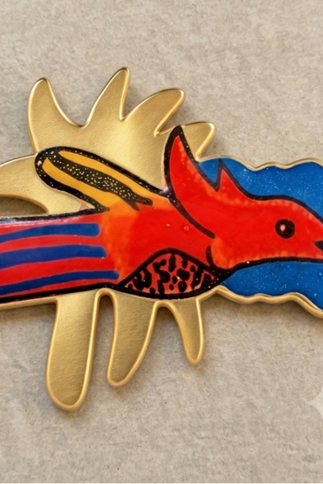 A colorful enameled bird with gold decorated bezel 