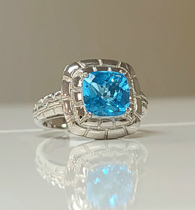 Sterling silver ring with cushion-cut blue topaz gemstone in ornate halo setting