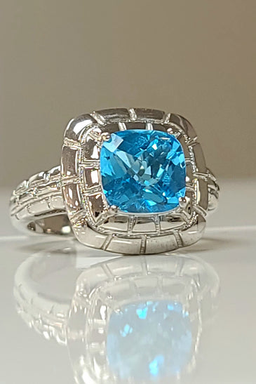 Sterling silver ring with cushion-cut blue topaz gemstone in ornate halo setting