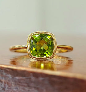 cushion cut peridot stone set in a stunning bezel with a 14k yellow gold band