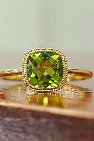 cushion cut peridot stone set in a stunning bezel with a 14k yellow gold band