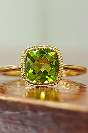 cushion cut peridot stone set in a stunning bezel with a 14k yellow gold band