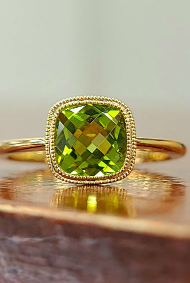 14kt yellow gold ring with green peridot oval center and textured halo bezel