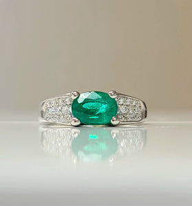 oval cut emerald surrounded by diamonds on a 18k white gold band