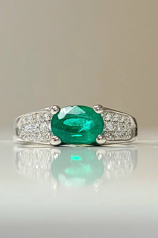 oval cut emerald surrounded by diamonds on a 18k white gold band
