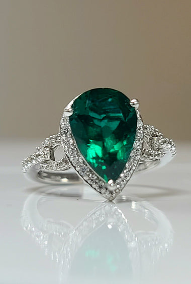 White gold ring with oval green lab emerald center and diamond halo, prong-set