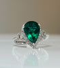 White gold ring with oval green lab emerald center and diamond halo, prong-set