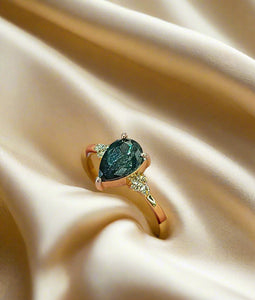 Yellow gold ring with teal oval gemstone and small diamond accents