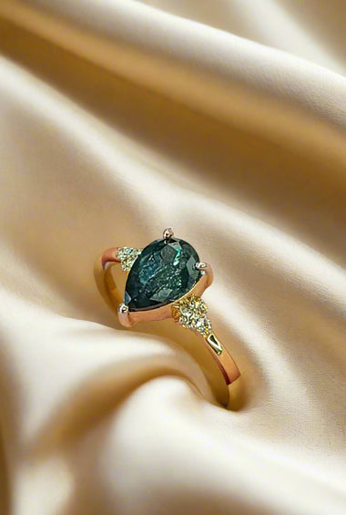Yellow gold ring with teal oval gemstone and small diamond accents