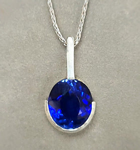 Sterling silver pendant with oval blue lab sapphire, half bezel, on chain