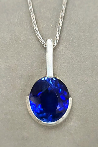 Sterling silver pendant with oval blue lab sapphire, half bezel, on chain
