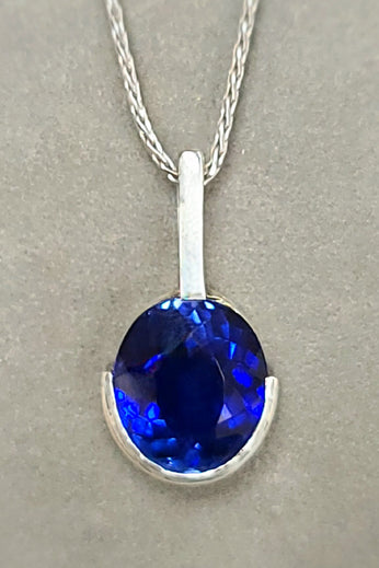 Sterling silver pendant with oval blue lab sapphire, half bezel, on chain