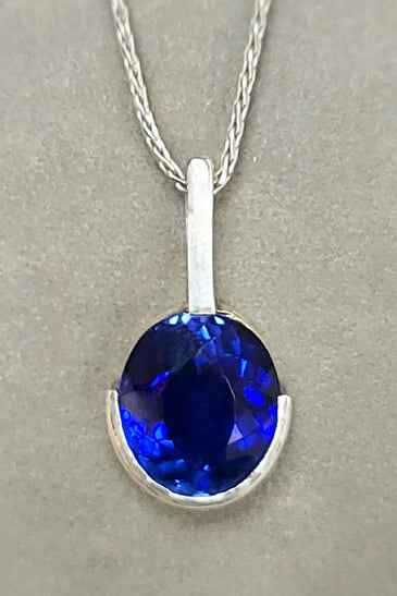 Sterling silver pendant with oval blue lab sapphire, half bezel, on chain