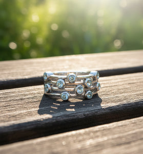 Sterling silver ring with round blue gemstones in a music-note style band