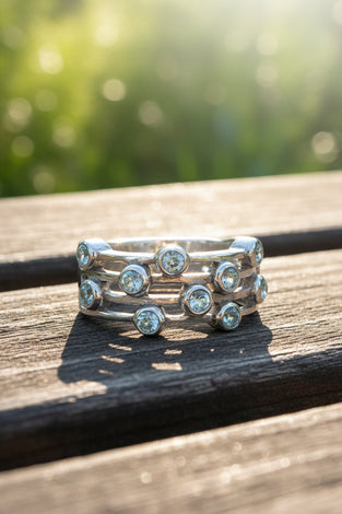 Sterling silver ring with round blue gemstones in a music-note style band