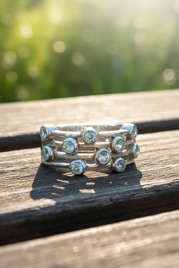 Sterling silver ring with round blue gemstones in a music-note style band