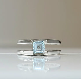 Sterling silver ring with square blue topaz centerpiece, open bypass design