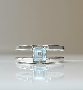 Sterling silver ring with square blue topaz centerpiece, open bypass design