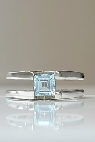 Sterling silver ring with square blue topaz centerpiece, open bypass design