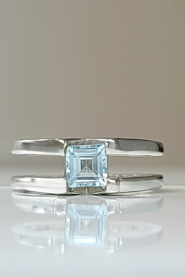 Sterling silver ring with square blue topaz centerpiece, open bypass design