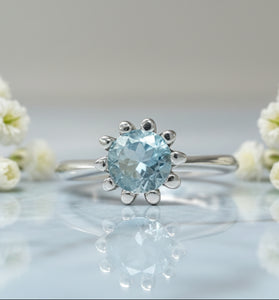 Sterling silver tulip ring with round blue topaz center and petal prongs