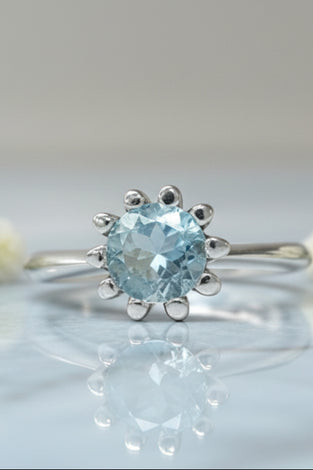 Sterling silver tulip ring with round blue topaz center and petal prongs
