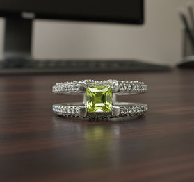 Sterling silver ring with green peridot center and sparkling side stones, V design