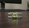 Sterling silver ring with green peridot center and sparkling side stones, V design