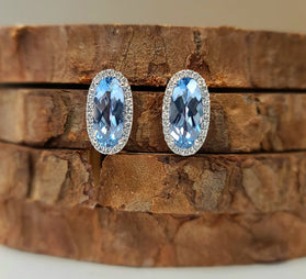 Oval blue gemstone earrings with diamond halo and white metal