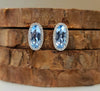 Oval blue gemstone earrings with diamond halo and white metal