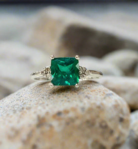 White gold lab emerald ring with square emerald-cut green stone and ornate side details