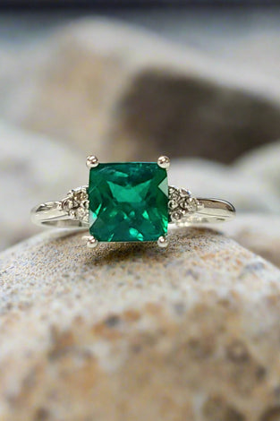 White gold lab emerald ring with square emerald-cut green stone and ornate side details
