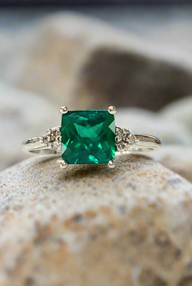 White gold lab emerald ring with square emerald-cut green stone and ornate side details