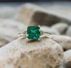 White gold lab emerald ring with square emerald-cut green stone and ornate side details