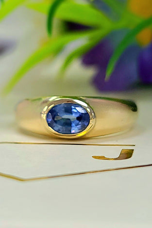 Yellow gold bezel-set sapphire ring with oval blue gemstone