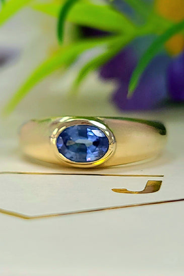 Yellow gold bezel-set sapphire ring with oval blue gemstone