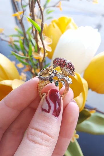14kt yellow gold bird ring with red oval stone, gold band, and small white flower accents