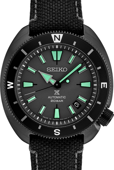 Men's black automatic watch with green indices, black bezel, and fabric strap.